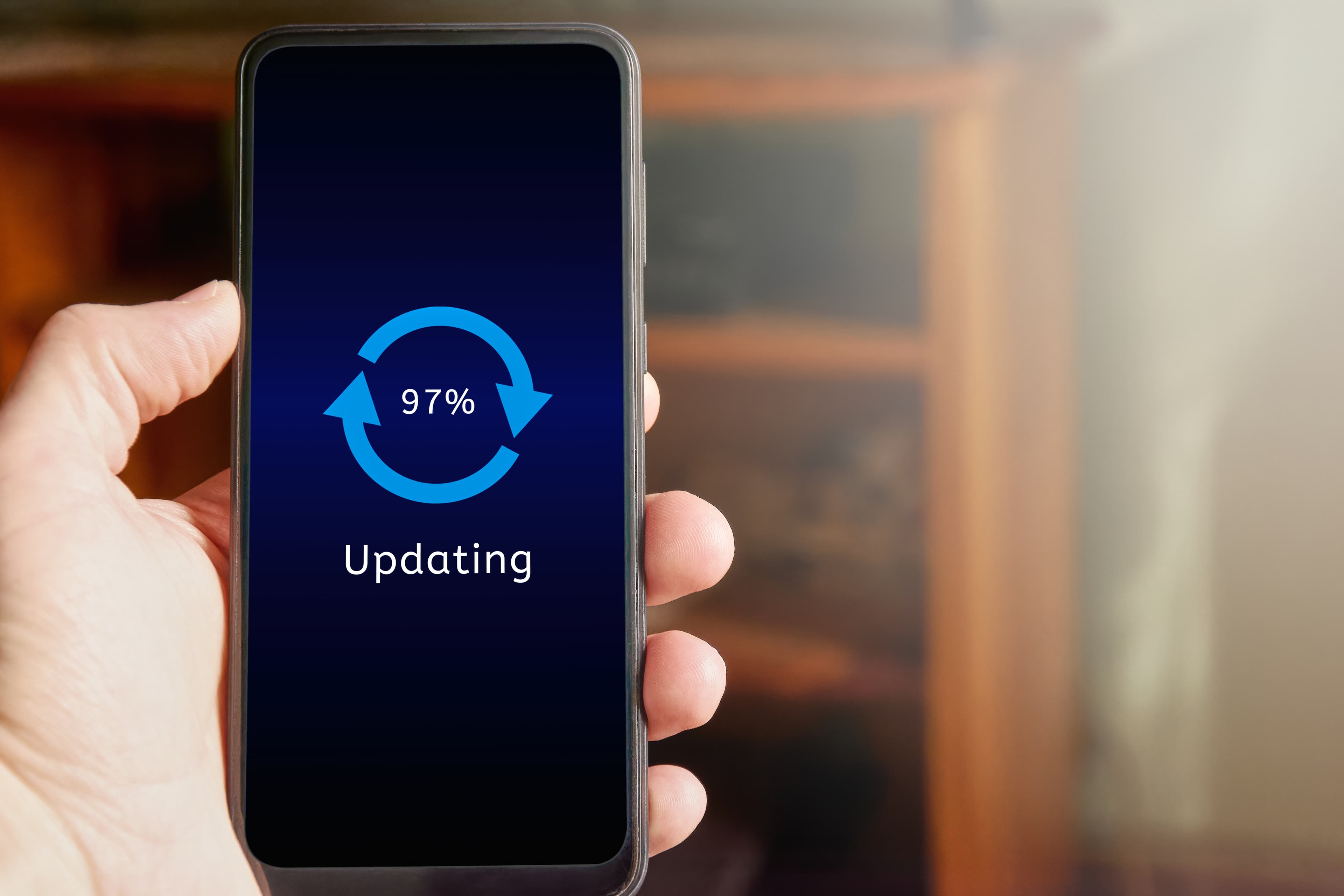 male hand holding mobile phone showing update interface icon with percentage progress screen man updating smartphone home